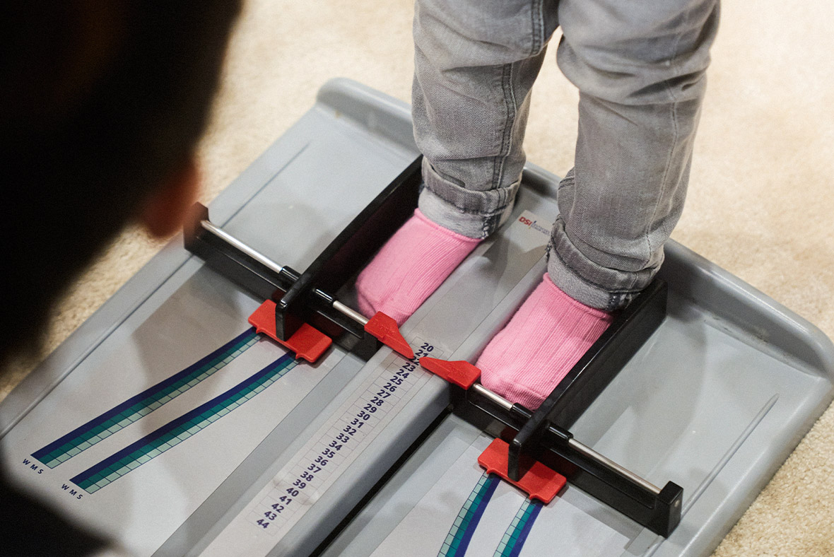 Measuring a child's shoe size with a specialized device in a shoe store