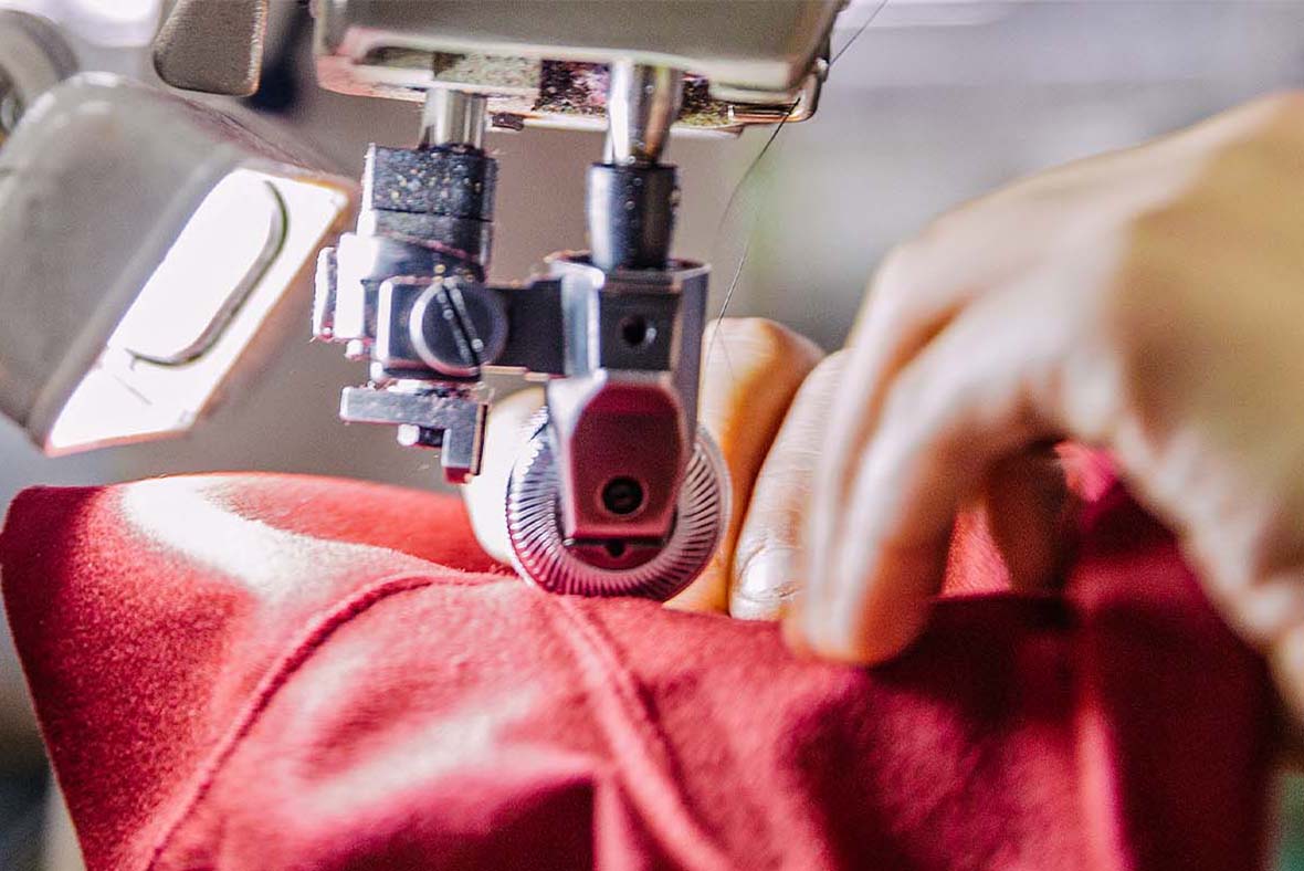 Handwerkskunst bei Think! – Detailaufnahme einer Näherin, die einen Lederschuh an einer Nähmaschine fertigt