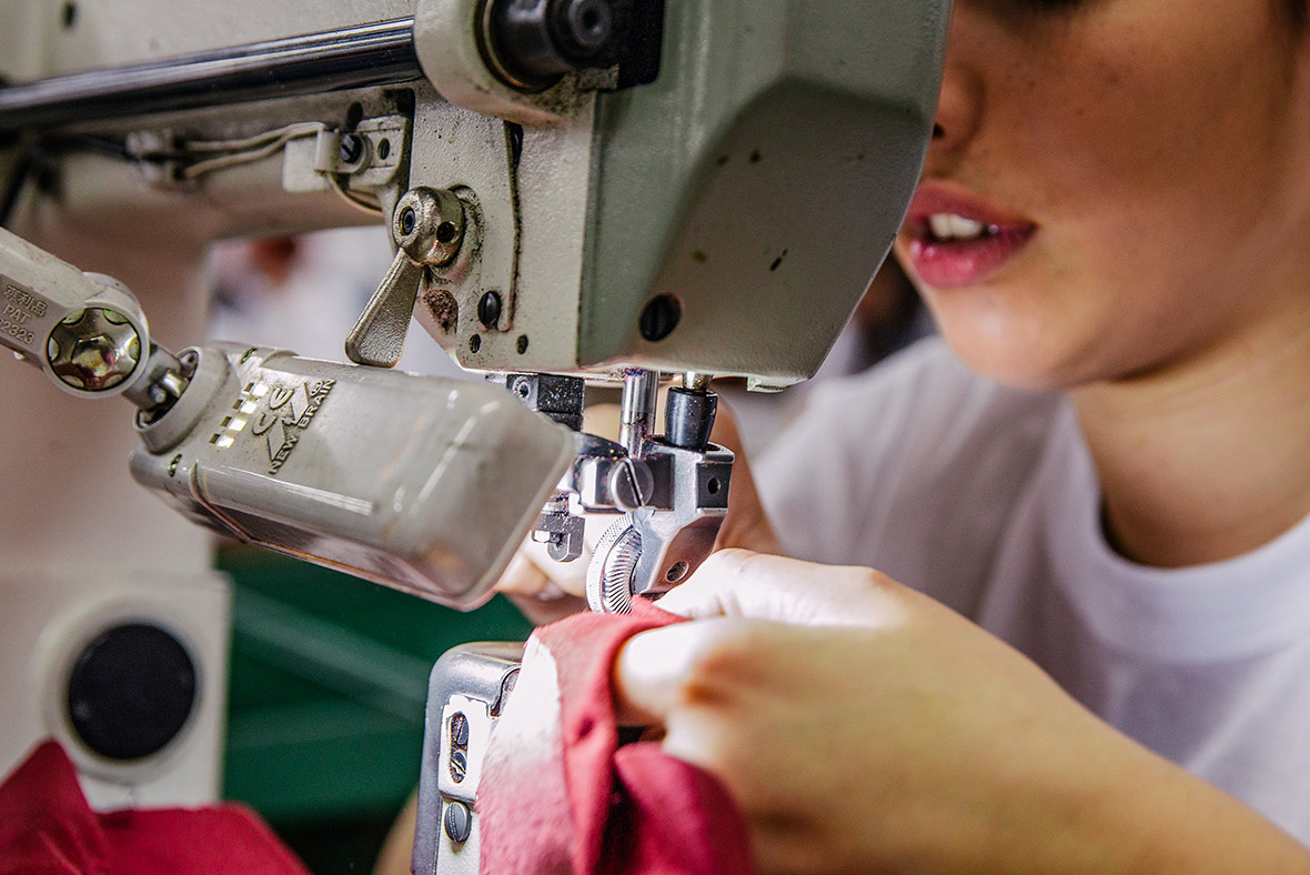 Handwerkskunst bei Think! – Detailaufnahme einer Näherin, die einen Lederschuh an einer Nähmaschine fertigt