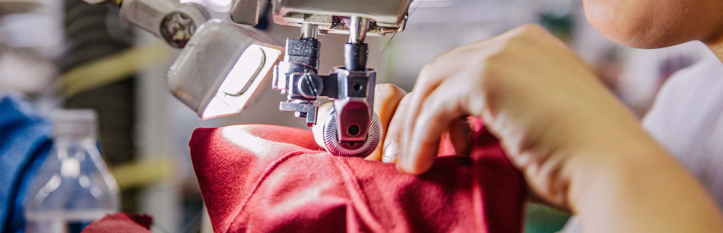 Handwerkskunst bei Think! – Detailaufnahme einer Näherin, die einen Lederschuh an einer Nähmaschine fertigt